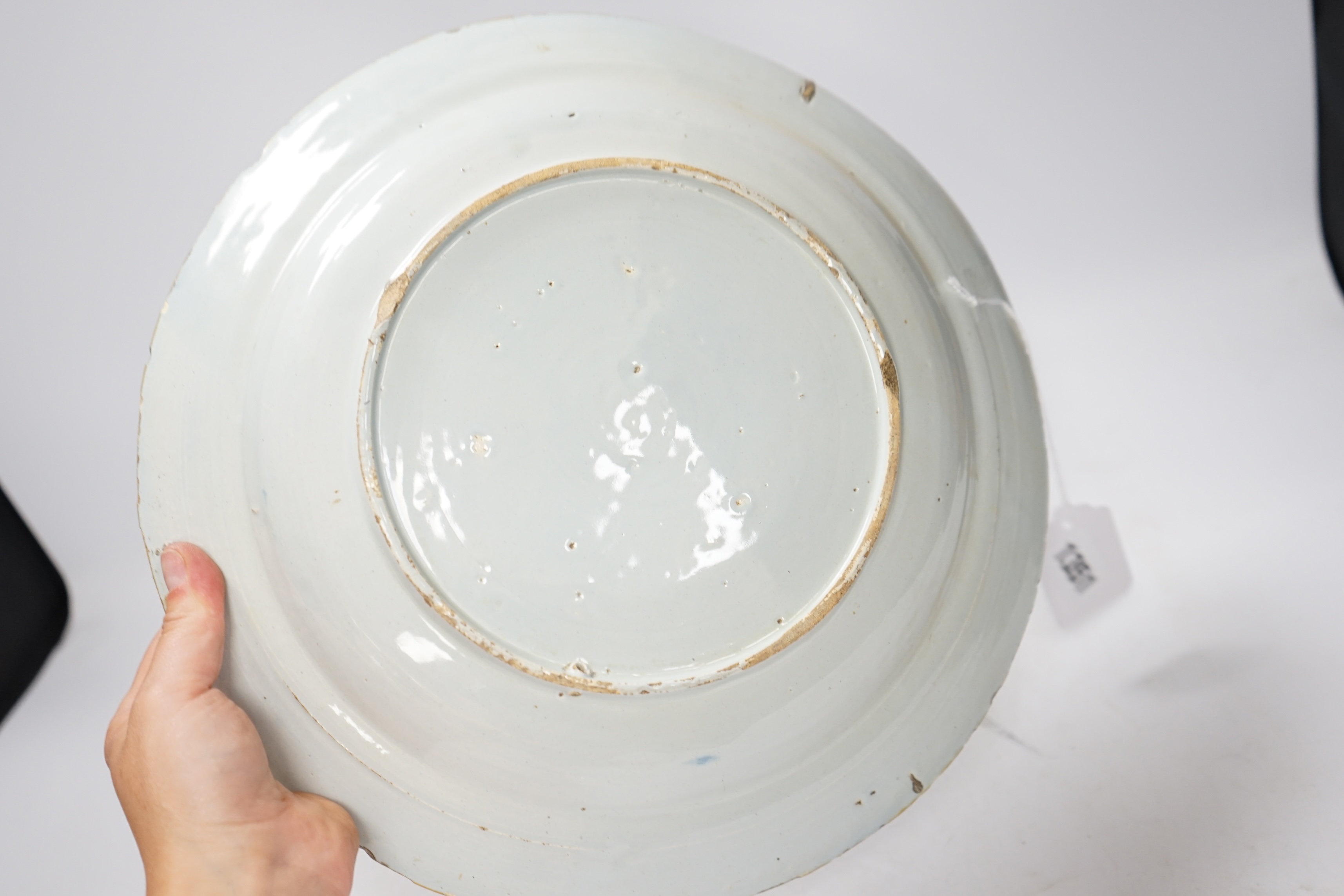 An 18th century delft blue and white dish, painted with a stylised peony and willow tree, 32cm diameter. Condition - fair, typical edge chipping all over